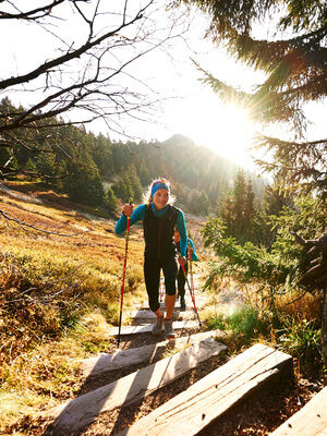 Eine Person wandert auf einem hölzernen Pfad durch den Bayerischen Wald.
