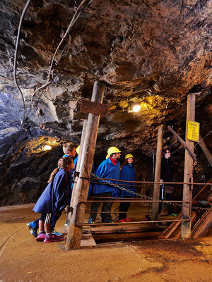 Eine Gruppe von Menschen durchquert den Tunnel des Historischen Besucherbergwerks Silberberg.