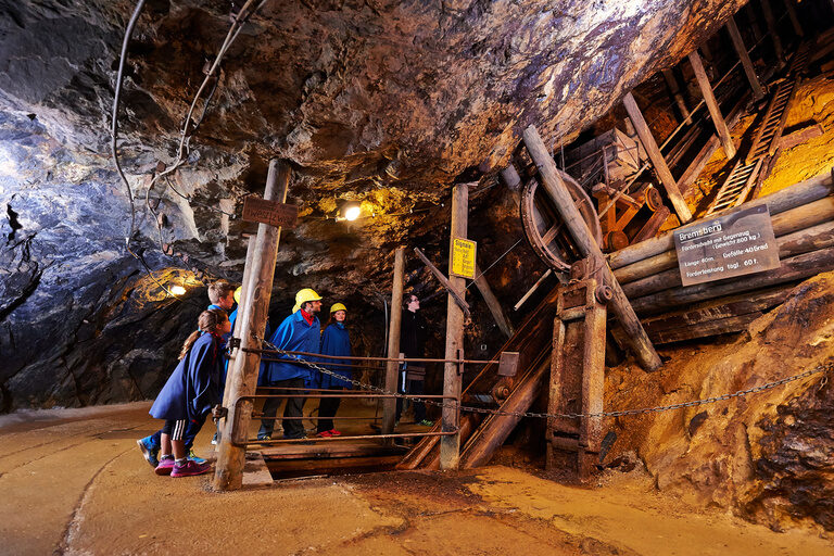 Eine Gruppe von Menschen durchquert den Tunnel des Historischen Besucherbergwerks Silberberg.
