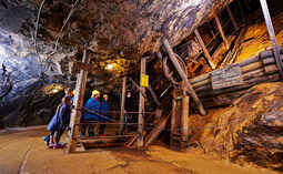 Eine Gruppe von Menschen durchquert den Tunnel des Historischen Besucherbergwerks Silberberg.